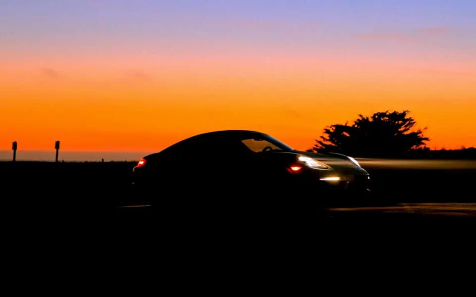 A car driving along a coastal road at dusk