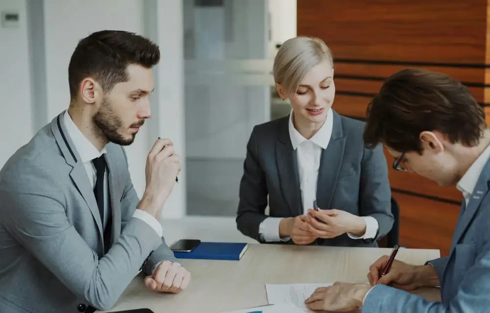 Three professionals sitting at a table in a client consultation