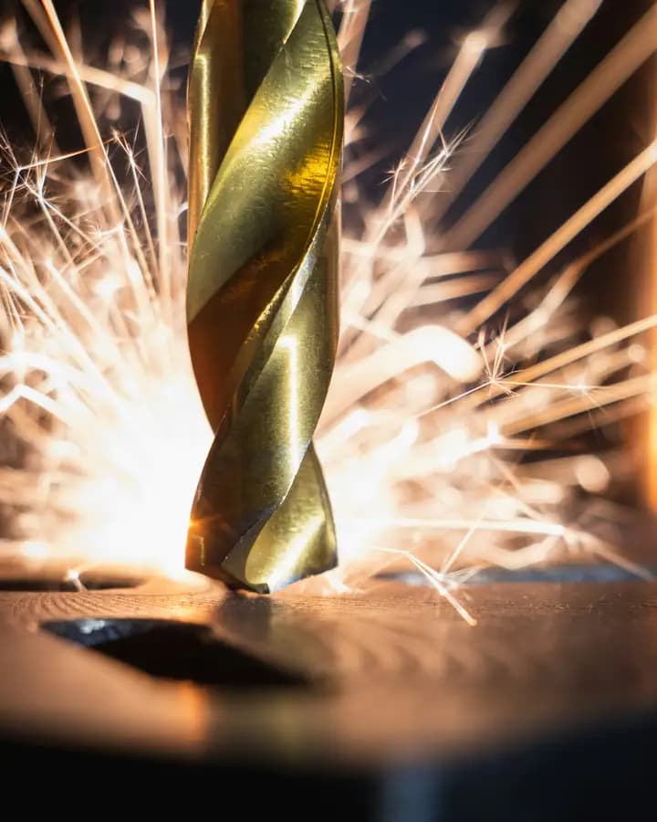 A drill bit cutting metal with a spray of sparks