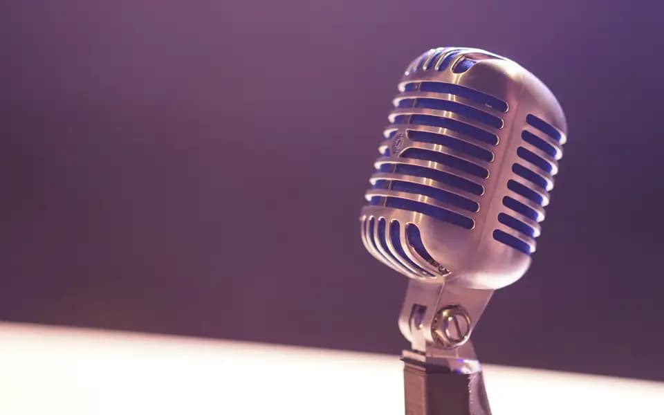 A chrome vintage microphone under purple stage light