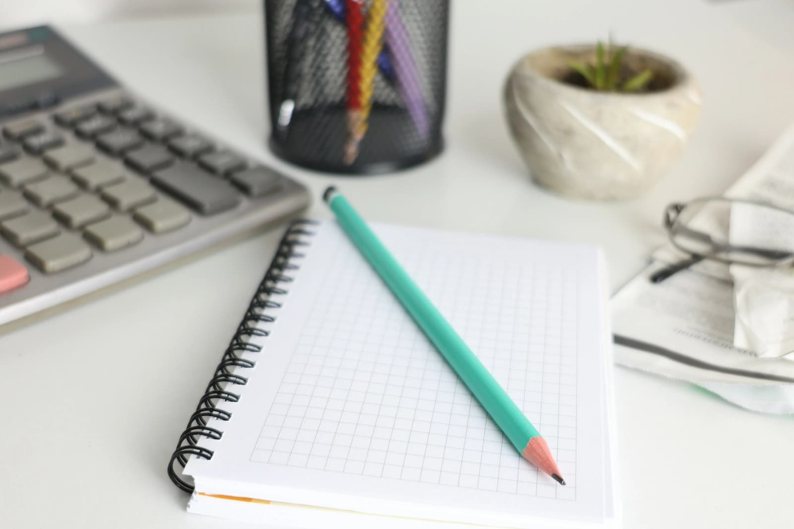 A calculator, notebook and pencil on a tidy desk