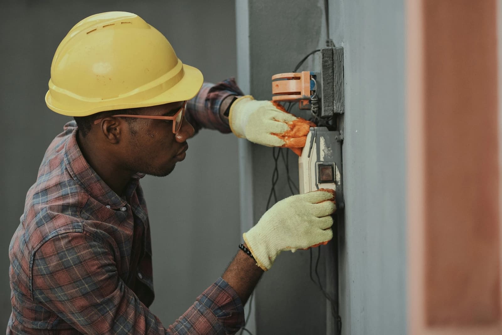 An electrician in a hard hat working on a wall installation
