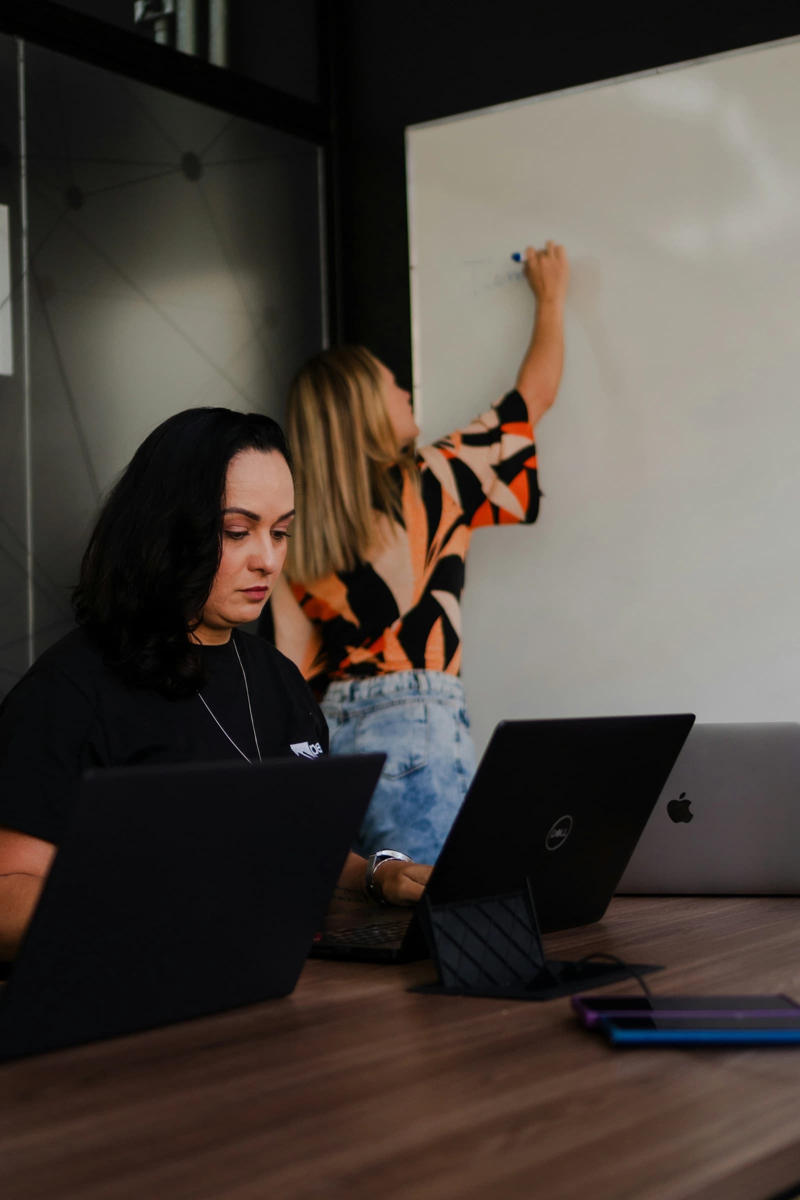 Two team members working on laptops in an office