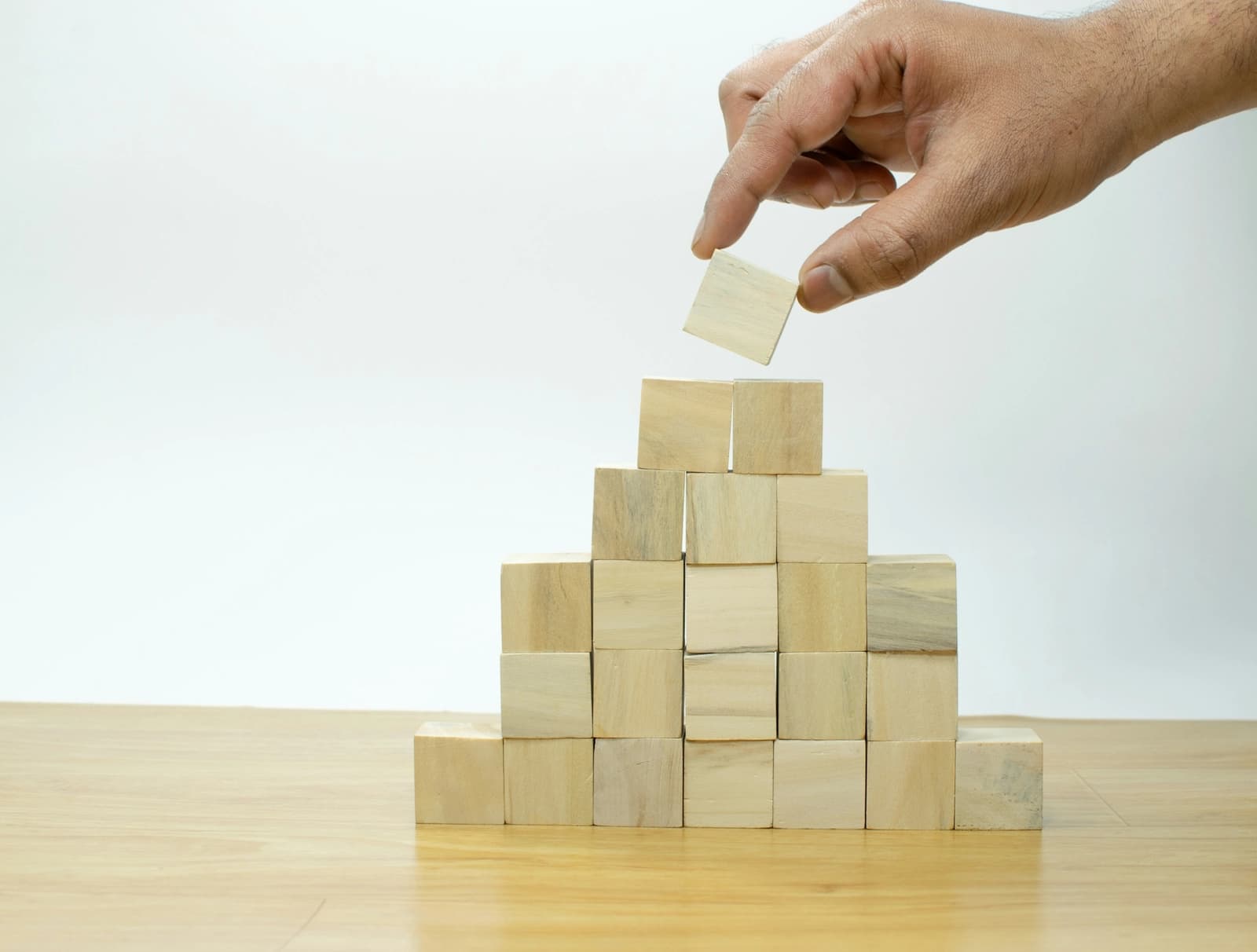 A hand placing a wooden block on a stack of blocks