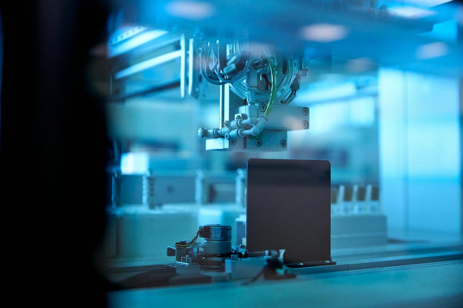 An automated machine with a camera and gripper inspecting a part on a production line