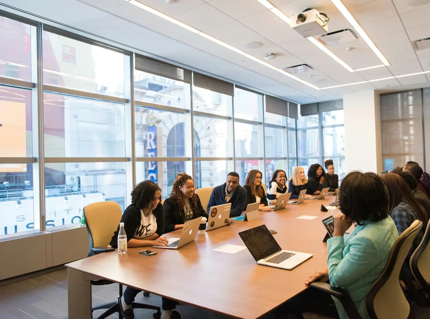 A team of professionals around a long meeting table with laptops in a bright office