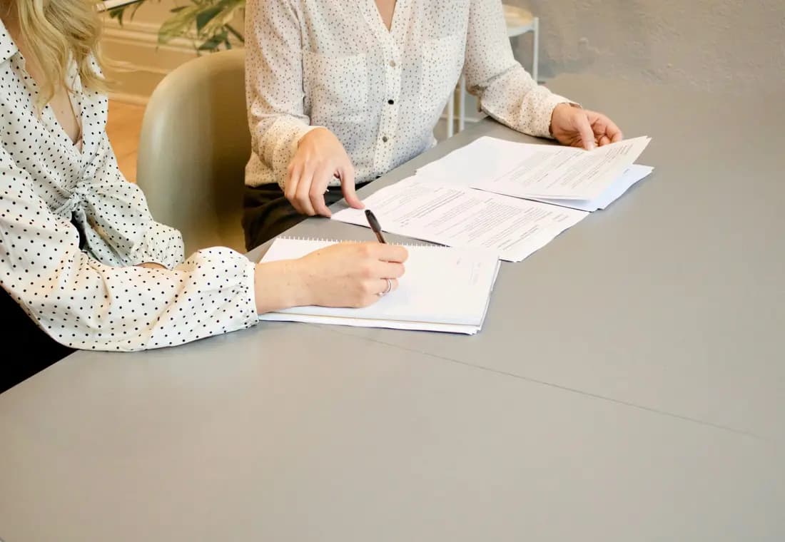Two people reviewing and signing documents at a table