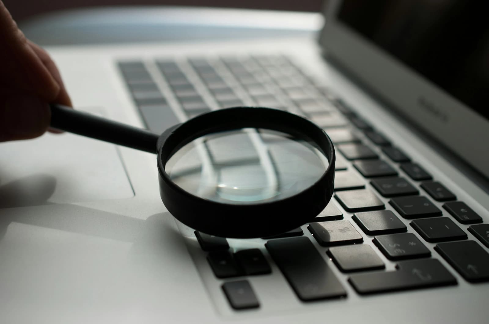 A magnifying glass held over a laptop keyboard